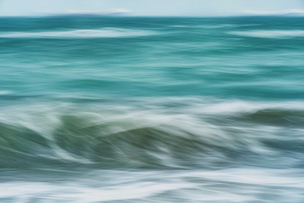 Ocean waves rolling gently with white foam under a clear blue sky