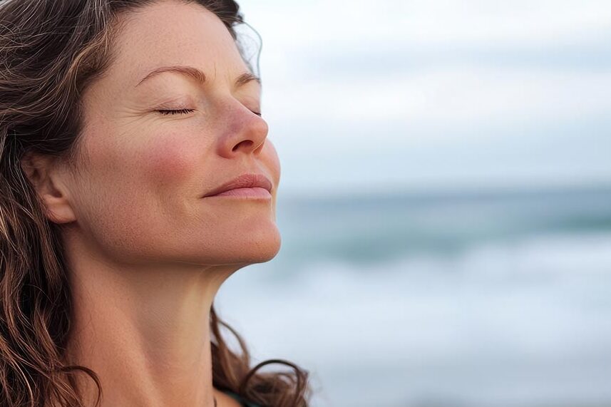A woman practicing breathwork exercises at the beach, focusing on relaxation and mental clarity.